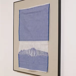 Obra textil de Macarena Cortés realizada con tela de algodón deshebrada en tonos azules y blancos, cuya forma evoca una montaña nevada. 60 x 43 cm, 2025, pieza única. Sin enmarcar.