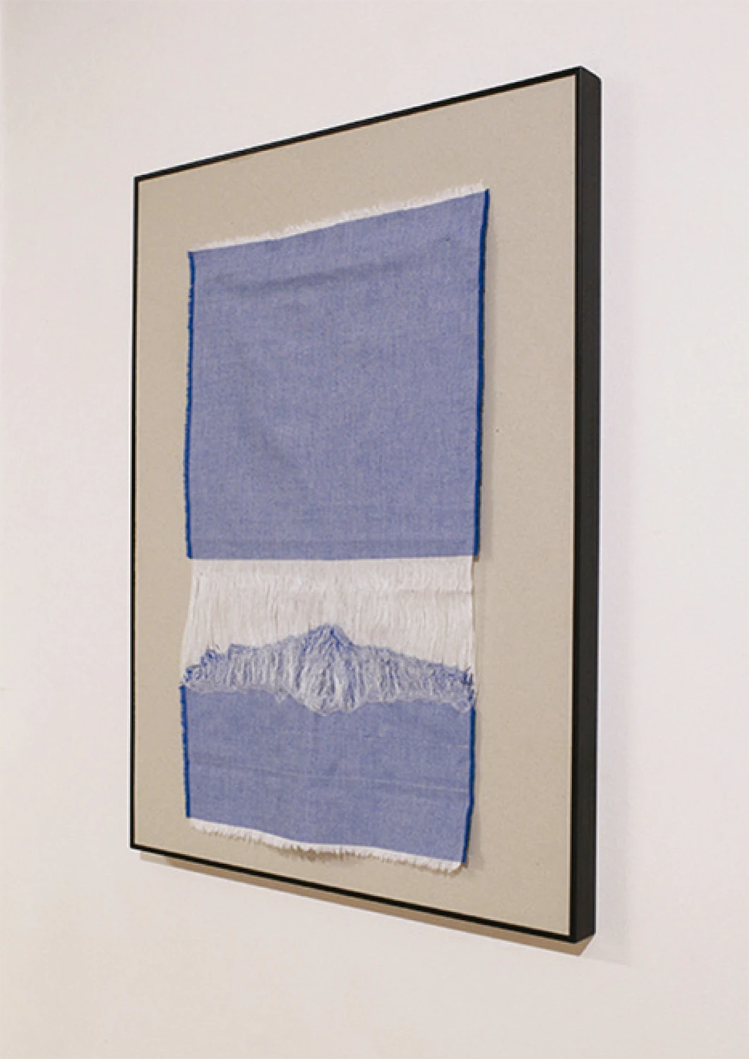 Obra textil de Macarena Cortés realizada con tela de algodón deshebrada en tonos azules y blancos, cuya forma evoca una montaña nevada. 60 x 43 cm, 2025, pieza única. Sin enmarcar.