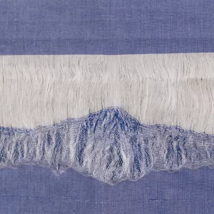 Detalle de obra textil de Macarena Cortés con fragmento de tela de algodón deshebrada en tonos azules y blancos que evoca una montaña nevada. 60 x 43 cm, pieza única, 2025.