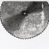Xilografía en blanco y negro de Adriana Asenjo que representa una sierra circular de gran tamaño, vista frontalmente y suspendida sobre un fondo blanco. El disco dentado presenta un orificio central y una superficie texturada con variaciones de tinta que enfatizan su materialidad y volumen. Xilografía sobre papel de arroz, 60 x 70 cm y 50 x 60 cm, edición P/A.